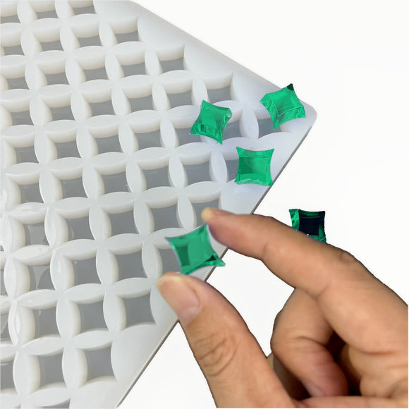 Hand holding a translucent emerald green star gummy beside the 2mL 219-cavity Star Gummy Mold