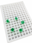 Angled view of a 2.625mL square gummy mold with 266 cavities and translucent emerald green square gummies on a clean white background