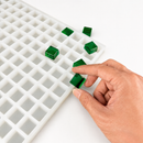 Moule à gummies carré de 4 mL - 192 cavites - échantillon de gummy tenu en main, avec des gummies vert émeraude