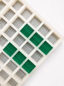 Close-up of a 7.4mL brick gummy mold with 70 cavities and emerald green brick gummies on a white background