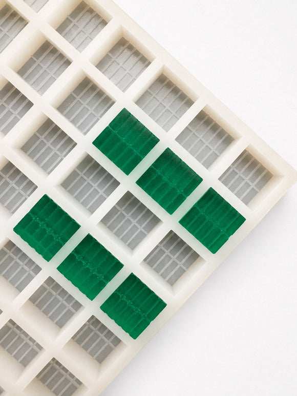 Close-up of a 7.4mL brick gummy mold with 70 cavities and emerald green brick gummies on a white background
